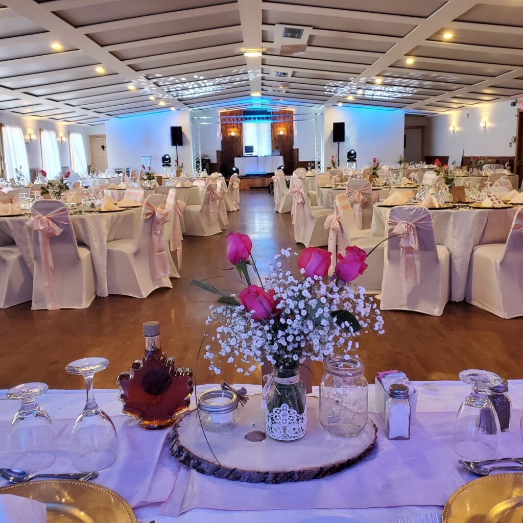 Salle de réception chez Farsa décorée pour un mariage avec tables montées et joli bouquet de roses et fleurs blanches à l'avant-plan