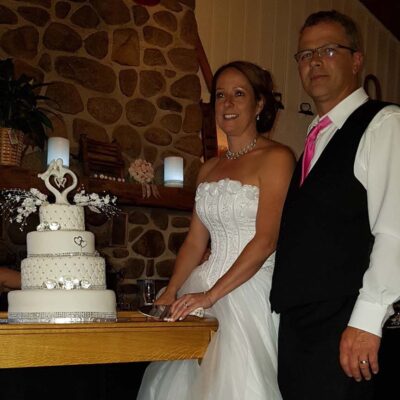 Les mariés posent à côté du gâteau de mariage
